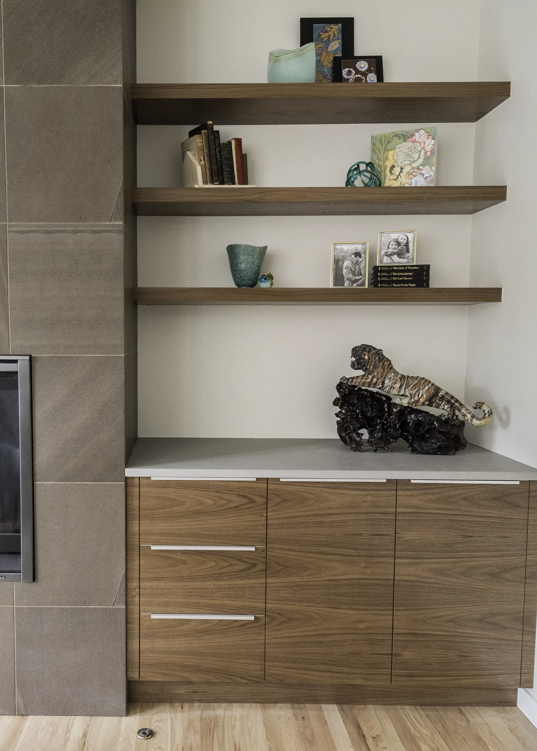 Detail of teak cabinetry and floating walnut shelves beside the living room fireplace