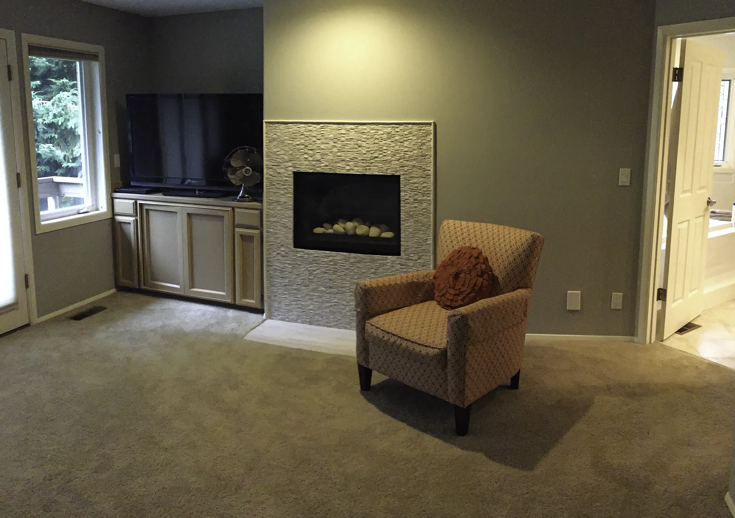 Primary bedroom fireplace before remodel with dated white textured surround