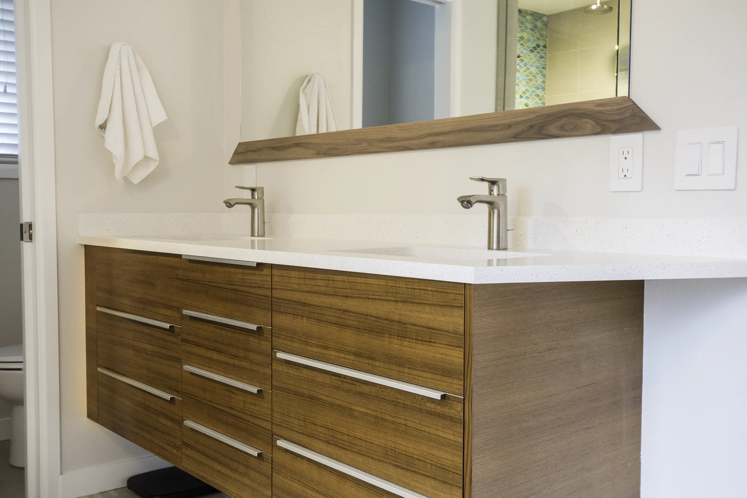 Primary bath floating double vanity with custom teak doors and walnut-framed mirror