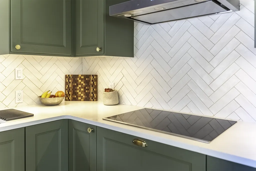 IKEA kitchen remodel cooktop corner with brass hardware and a herringbone tile wall