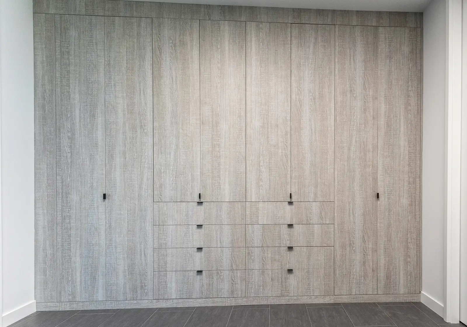 Custom closet wardrobe wall in grey oak with slab doors and integrated drawers