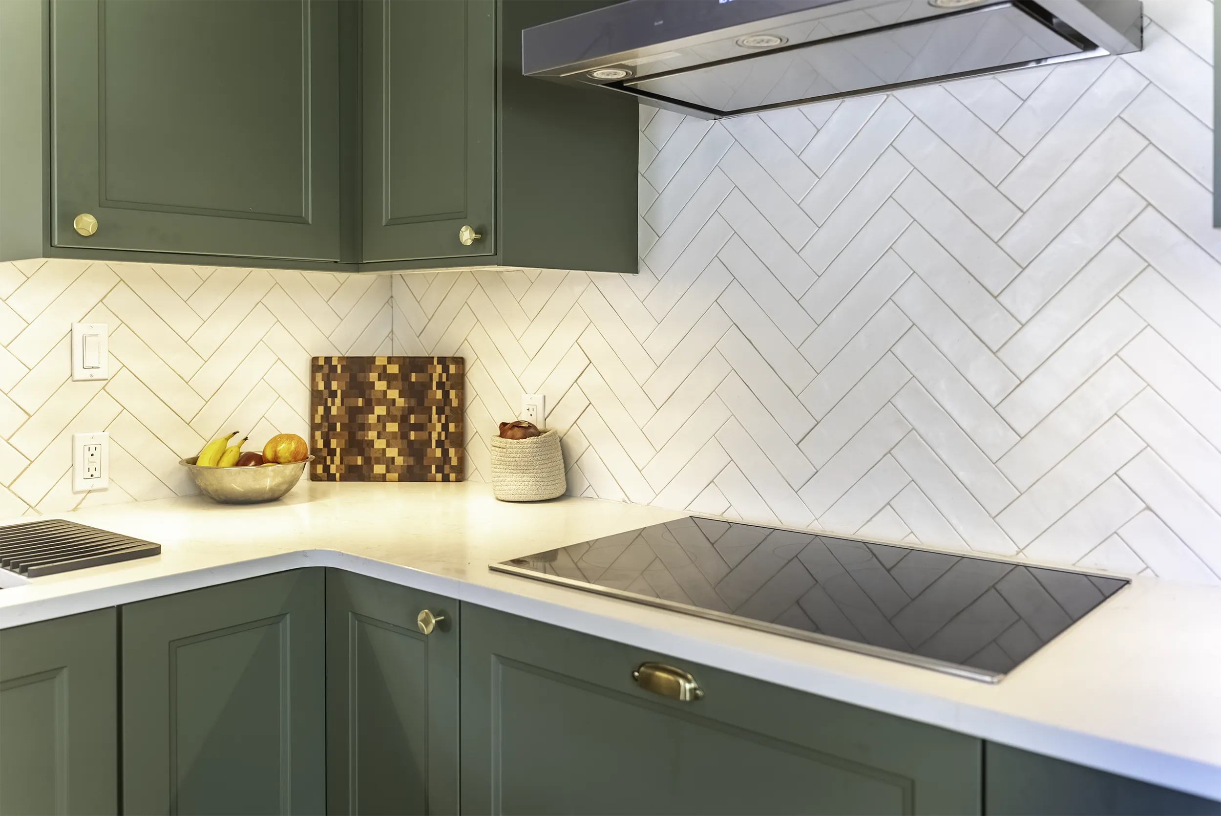Brass cabinet hardware and herringbone tile by the induction cooktop, West Seattle kitchen remodel